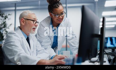 Ospedale medico: Due medici parlano e usano il computer, diagnostica e test informazioni, trovare cura e soluzione. Ricerca clinica sanitaria con team di diversi professionisti contemporanei che lavorano Foto Stock