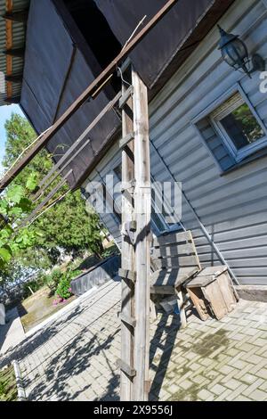 Scala in legno appoggiata a un edificio esterno nel cortile di una casa Foto Stock