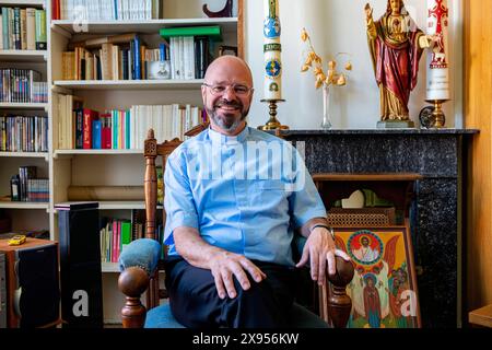 Portait sacerdote cattolico Tilburg, Paesi Bassi. Living Room Ritratto di un sacerdote cattolico di 56 anni seduto sulla sua sedia da lettura, mentalmente e spiritualmente preparandosi per la sua nuova commissione datagli dal suo Vescovo. MRYES Tilburg Parochie Binnenstad Nootd-Brabant Nederland Copyright: XGuidoxKoppesxPhotox Foto Stock