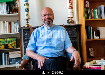 Portait sacerdote cattolico Tilburg, Paesi Bassi. Living Room Ritratto di un sacerdote cattolico di 56 anni seduto sulla sua sedia da lettura, mentalmente e spiritualmente preparandosi per la sua nuova commissione datagli dal suo Vescovo. MRYES Tilburg Parochie Binnenstad Nootd-Brabant Nederland Copyright: XGuidoxKoppesxPhotox Foto Stock