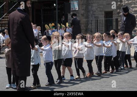 Un rabbino e i suoi giovani studenti marciano in formazione mentre celebrano il lag B'Omer 2024. A Brooklyn, New York. Foto Stock