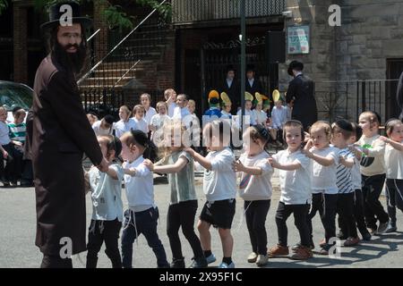 Un rabbino e i suoi giovani studenti marciano in formazione mentre celebrano il lag B'Omer 2024. A Brooklyn, New York. Foto Stock