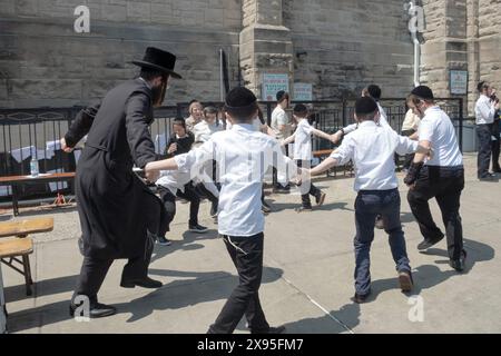 A una celebrazione del LAG B'Omer a Brooklyn, un rabbino vivace balla con i suoi giovani studenti maschi. A Williamsburg, 2024. Foto Stock