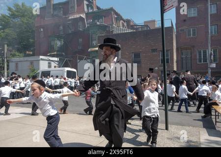 Un rabbino e i suoi allievi ballano a una celebrazione del LAG B'Omer in una strada chiusa a Williamsburg, Brooklyn, New York. Foto Stock