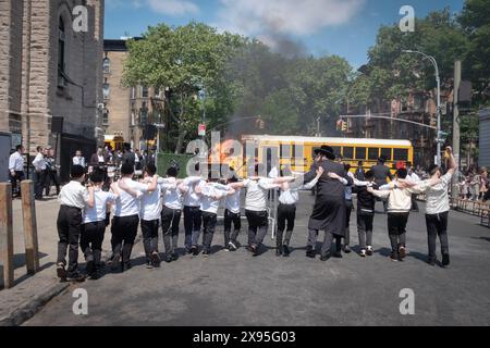 Durante le celebrazioni del Lag Bomer 2024, un rabbino e i suoi studenti ballano in linea verso il fuoco tradizionale. A Brooklyn, New York. Foto Stock