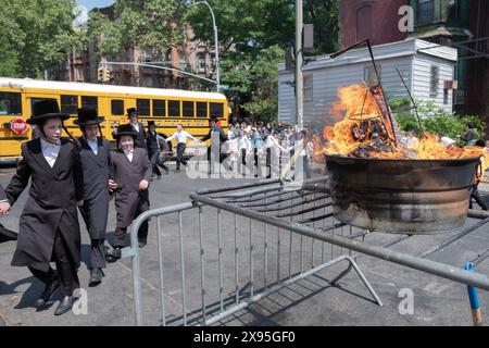 Durante una celebrazione del LAG B'Omer, una classe di giovani uomini e i loro insegnanti di rabbino ballano accanto al fuoco tradizionale. A Brooklyn, New York. Foto Stock