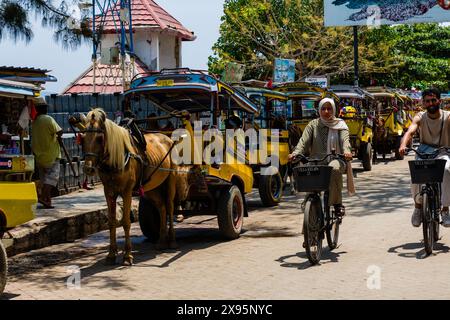 I tradizionali carretti a cavallo (Cidomo) aspettano accanto al porto sulla strada principale dell'isola di Gili Trawangan in Foto Stock