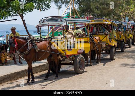 GILI TRAWANGAN, INDONESIA - 10 NOVEMBRE 2023: Carrozze trainate da cavalli tradizionali (Cidomo) sulla strada principale di Gili Trawangan nelle isole indonesiane Gili Foto Stock