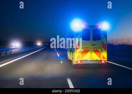 Auto ambulanza veloce di servizio medico di emergenza su autostrada di notte. Temi assistenza sanitaria, soccorso e urgenza. Foto Stock