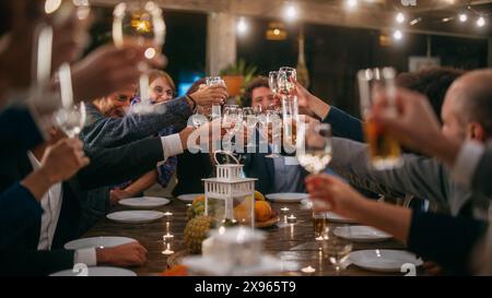 Grande cena con una piccola folla di amici multietnici che festeggiano in un ristorante. I bellissimi padroni di casa, felici, propongono un brindisi e alzano i bicchieri da vino mentre si siedono a un tavolo la sera. Foto Stock