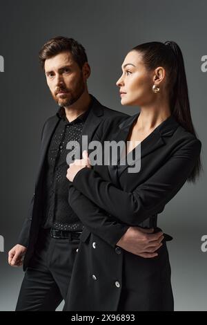 Un uomo e una donna vestiti elegantemente stanno fianco a fianco, trasudando amore e grazia. Foto Stock
