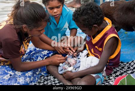 Bambini aborigeni che si prendono cura di un canguro orfano (joey), Nyinyikay Homeland, East Arnhem Land, Northern Territory, Australia, Pacifico Foto Stock