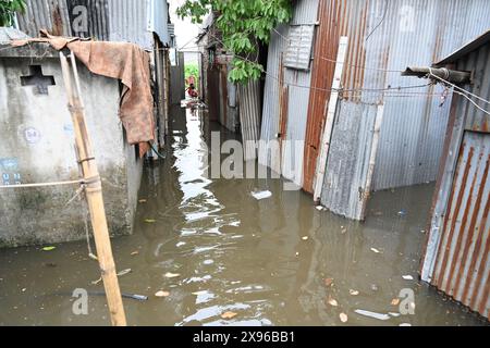 Gli slum guardano attraverso un cortile allagato a seguito di forti piogge dopo l'atterraggio del ciclone Remal a Balumath slum a Dacca, Bangladesh, il 29 maggio 2024 Foto Stock