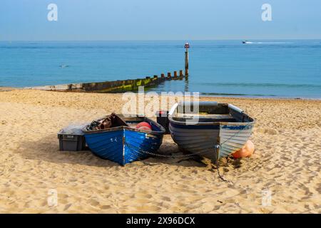 Aum Chine Beach, Bournemouth, Regno Unito - 9 settembre 2023: Due barche a remi sulla spiaggia sabbiosa di fronte a una groyne di legno che si getta nel mare. Foto Stock