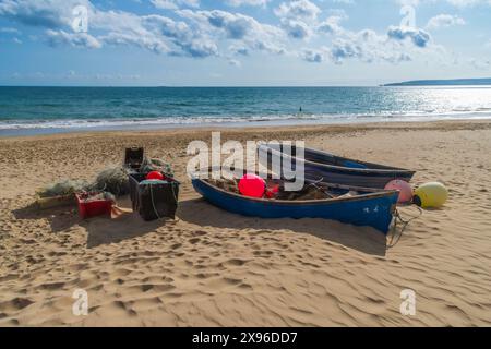 Branksome Dene Beach, Bournemouth, Regno Unito - 6 ottobre 2023: Barche a remi e reti da pesca su una spiaggia di sabbia vuota. Foto Stock