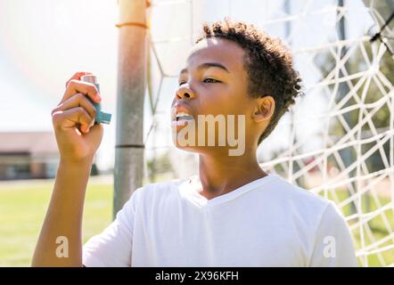 Il bambino sta usando un inalatore per asma nel parco Foto Stock