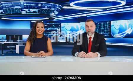 TV Live News Program: Due diversi presentatori professionisti che riportano gli eventi. Televisione via cavo, Newsroom Studio: White male, Black Female Anchors Talk. Concetto di rete di trasmissione mockup Foto Stock