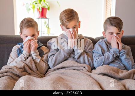 tosse i ragazzi dei piccoli fratelli a casa che hanno influenza sul divano Foto Stock