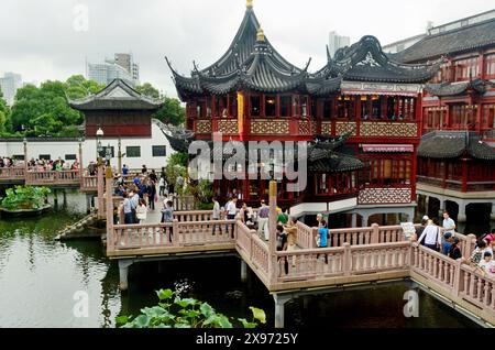 I visitatori osservano i pesci rossi e le carpe di Koi che nuotano nel lago di Yu o nei giardini di Yuyuan, Shanghai, Cina Foto Stock