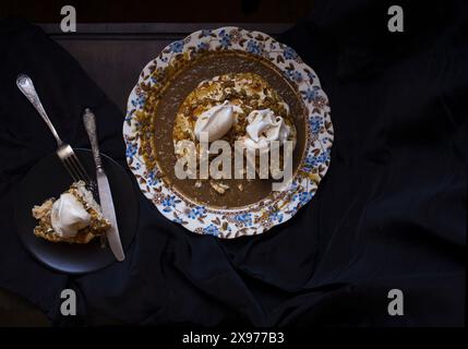 Foto da tavolo della torta Pavlova con salsa di caffè e noci su un piatto vintage in porcellana inglese con motivo floreale blu e marrone Foto Stock