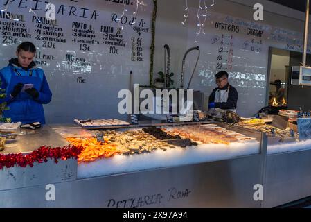 Oporto, Portogallo - 23 novembre 2023: Pescivendoli nel negozio di pesce con ostriche fresche, ricci di mare viola e gamberi in un negozio di pesce gourmet a Bolhao M. Foto Stock