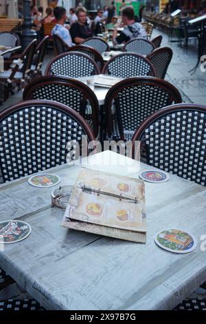 Bucarest, Romania - 28 luglio 2023: Ristorante all'aperto in via Covaci nel centro storico di Bucarest, con menu a libro su tavola in primo piano Foto Stock