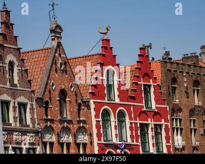 Edifici storici colorati con facciate ornate e frontoni sotto un cielo blu, facciate di case storiche in una città medievale vicino al fiume, Bruges, Belgio Foto Stock