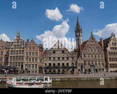 Fila di edifici storici lungo un canale con barche sotto un cielo azzurro limpido con nuvole, skyline di una città storica sul fiume con vecchie facciate e. Foto Stock