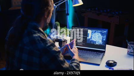 Informatico che aggiorna l'algoritmo di apprendimento automatico dell'intelligenza artificiale, scrivendo script di codice binario. Lo specialista IT del telelavoro negli uffici di appartamenti utilizza la programmazione per aggiornare l'IA, la telecamera B. Foto Stock