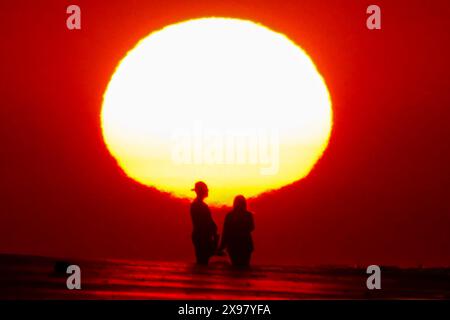 Isola di Palms, Stati Uniti. 29 maggio 2024. Una coppia, sagomata dall'alba, si fa un selfie sulla spiaggia mentre un'onda di calore attraversa la regione portando le temperature negli anni '90, 29 maggio 2024 a Isle of Palms, South Carolina. Crediti: Richard Ellis/Richard Ellis/Alamy Live News Foto Stock