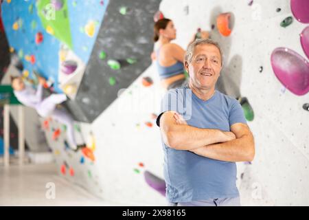 Un uomo anziano sicuro di sé in piedi nel centro sportivo di arrampicata Foto Stock