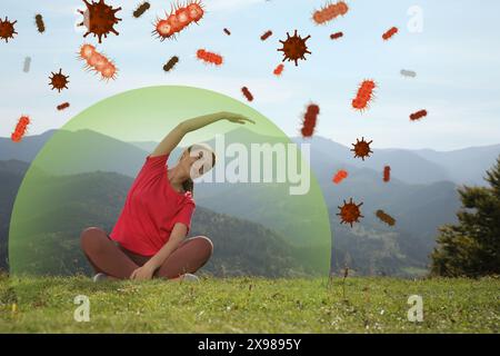 Donna felice che pratica yoga in montagna. Bolla intorno a lei che simboleggia forti virus di blocco dell'immunità, illustrazione Foto Stock