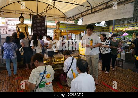 Persone che fanno offerte di fiori di calendula e incenso il giorno Vesak 2024, al Wat Phra Pathommachedi Ratcha Wora Maha Wihan, Nakhon Pathom, Thailandia Foto Stock