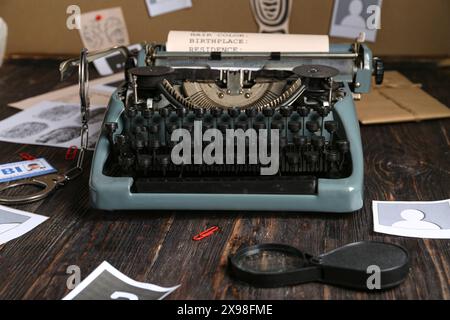 Macchina da scrivere retrò, lente di ingrandimento, manette e fascicoli criminali su un tavolo di legno Foto Stock