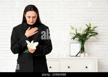 Giovane donna con fiori di giglio funebre in camera Foto Stock