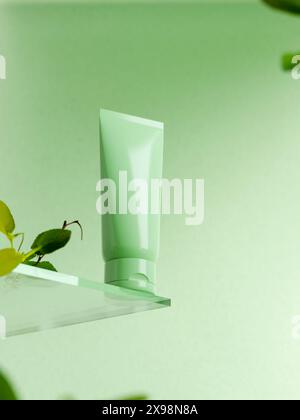 Un tubo verde su un piedistallo di vetro su sfondo verde. un modello di prodotto di bellezza su uno striscione verde. lozione per il corpo, crema per le mani o mockup con tubo detergente. 3 Foto Stock