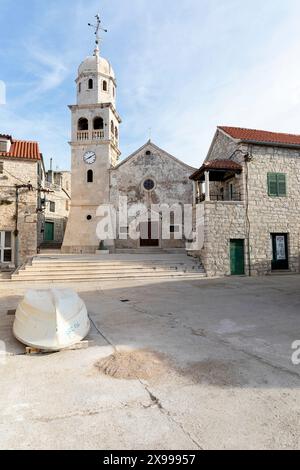 Piccola barca da pesca sulla piazza di fronte a una chiesa in un piccolo pittoresco villaggio di Prvic Sepurine sull'isola di Prvic nell'arcipelago di Sibenico in Croazia Foto Stock