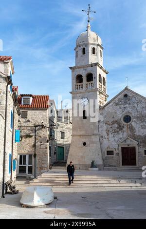 Uomo locale di fronte a una chiesa in un piccolo pittoresco villaggio di Prvic Sepurine sull'isola di Prvic nell'arcipelago di Sibenico in Croazia Foto Stock