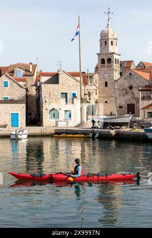 Kayak turistico in mare visitando la splendida parte vecchia di un villaggio Prvic Sepurine sull'isola di Prvic nell'arcipelago di Sibenik in Croazia Foto Stock