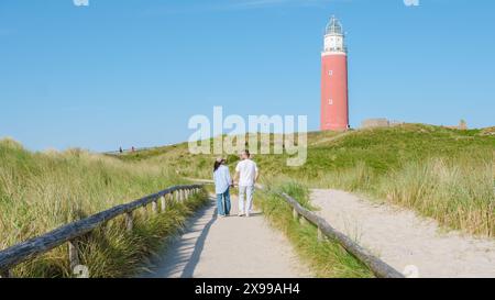 Una coppia di piacevoli passeggiate lungo un sentiero tortuoso vicino all'iconico faro di Texel, godendosi le viste panoramiche sulla costa in una giornata tranquilla. Uomo e donna presso l'iconico faro rosso di Texel Paesi Bassi Foto Stock