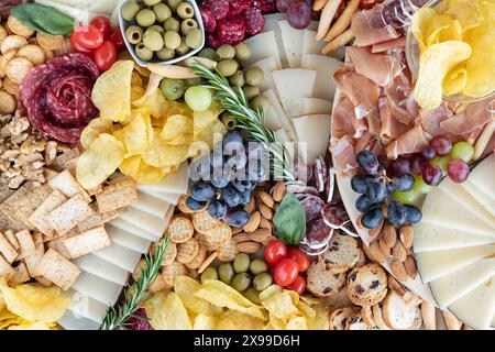 Tagliere di salumi piatti riccamente disposti con una varietà di affettati, una selezione di formaggi stagionati, cracker e grissini, noci e olive Foto Stock