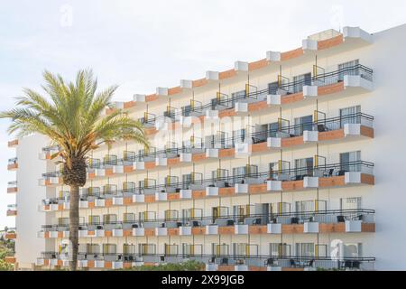 Cala d'Or, Spagna; 04 maggio 2024: Facciata con balconi di un vecchio edificio di appartamenti turistici nella città di Cala d'Or in una mattinata di sole Foto Stock