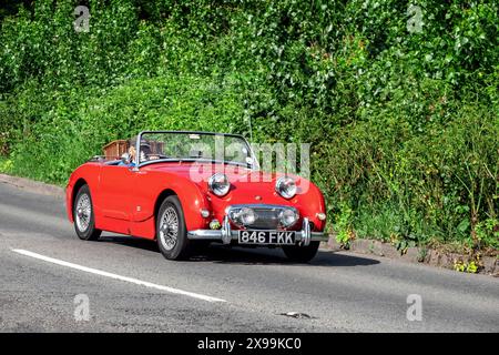 Austin Healey Sprite MkI che guida lungo una strada di campagna inglese Foto Stock
