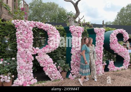 I visitatori posano di fronte all'esposizione floreale RHS all'annuale Chelsea Flower Show di Londra Foto Stock