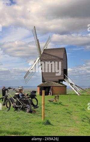 Mulino a vento Brill Post Mill nel Buckinghamshire Regno Unito, con ciclisti seduti su una panchina Foto Stock