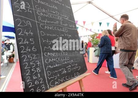 Hay Festival, Hay on Wye, Powys, Galles, Regno Unito – giovedì 30 maggio 2024 – i visitatori passano davanti alla bacheca informativa di aggiornamento con i dettagli sui cambiamenti di sede e le cancellazioni degli eventi - l'Hay Festival ha molte cancellazioni anche quest'anno alcune in relazione a Baillie Gifford - foto Steven May / Alamy Live News Foto Stock