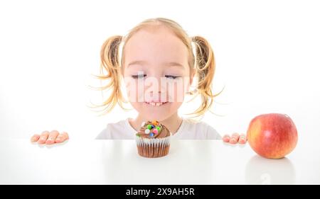 Bambina con Cupcake e mela su sfondo bianco Foto Stock