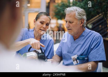 Medico donna che versa caffè per collega in mensa all'ospedale Foto Stock
