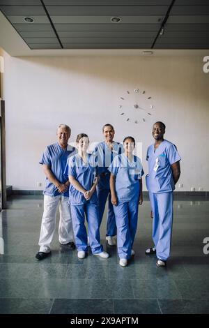 Ritratto di un team sanitario diverso sorridente in scrub blu in piedi insieme in ospedale Foto Stock