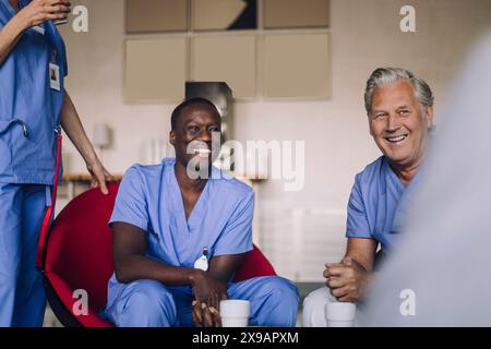 Medici felici maschili e femminili in mensa dell'ospedale durante la pausa caffè Foto Stock